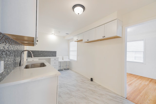 kitchen featuring sink, a healthy amount of sunlight, white cabinetry, and tasteful backsplash