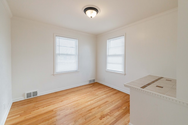 empty room with light wood-type flooring and crown molding