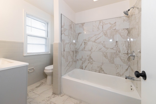 full bathroom featuring tile walls, vanity, tiled shower / bath combo, and toilet