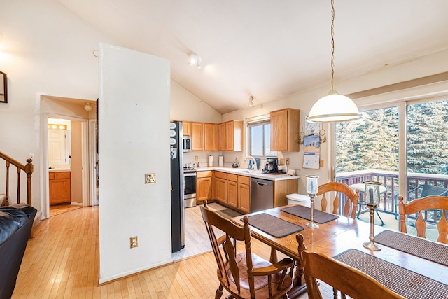 dining room featuring sink, light wood-type flooring, and high vaulted ceiling