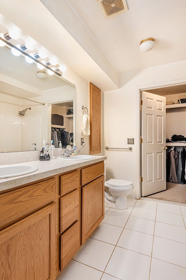 bathroom featuring toilet, a shower, vanity, and tile patterned floors