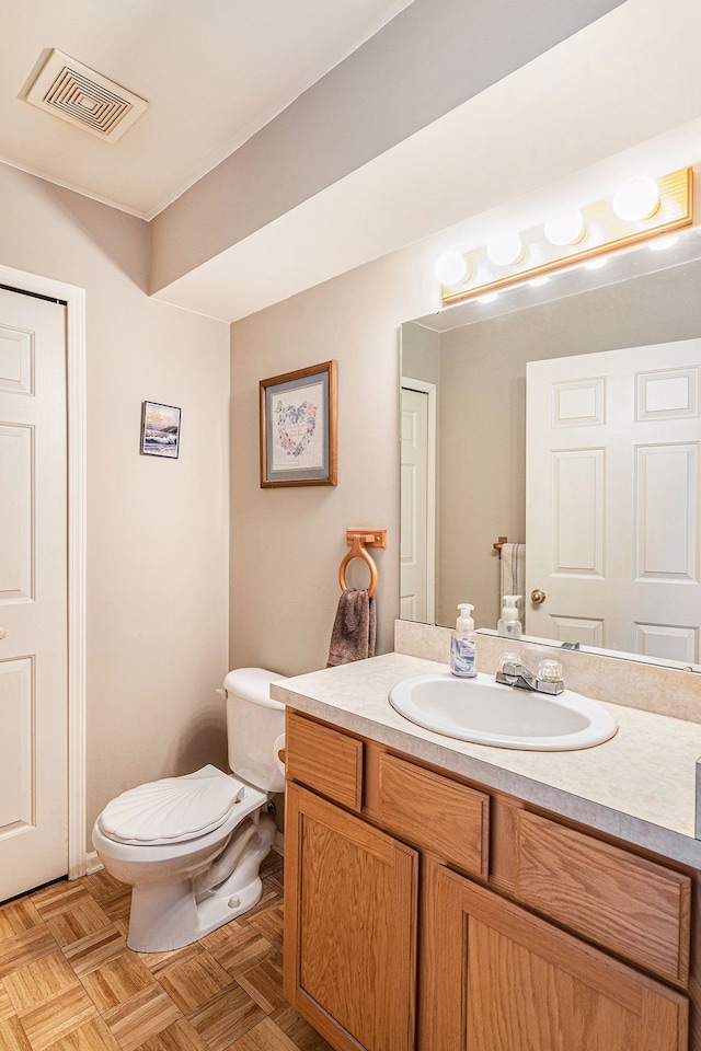 bathroom featuring toilet, parquet flooring, and vanity