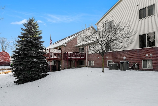 snow covered rear of property with central AC and a wooden deck