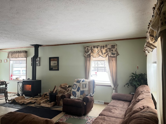 carpeted living area featuring crown molding, visible vents, a wood stove, a textured ceiling, and baseboards