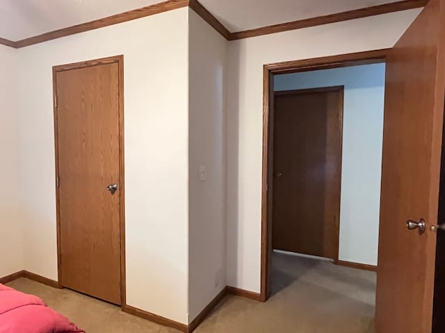 hallway featuring light carpet, ornamental molding, and baseboards