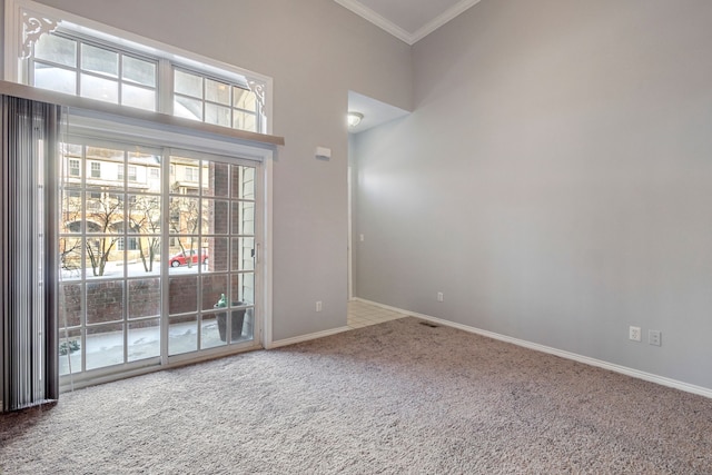 carpeted empty room with ornamental molding and a high ceiling