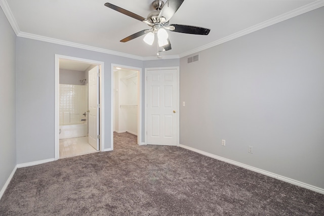 unfurnished bedroom with a closet, connected bathroom, carpet, a walk in closet, and ceiling fan