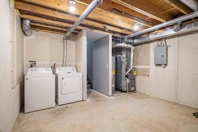 basement featuring electric panel, washing machine and clothes dryer, and heating unit