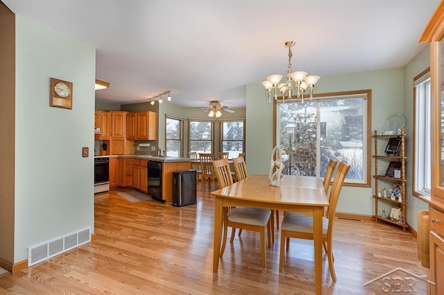 dining area featuring ceiling fan with notable chandelier, light hardwood / wood-style flooring, and sink