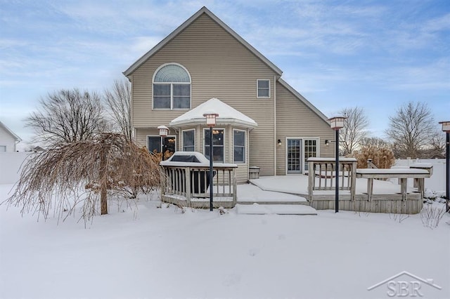 snow covered rear of property featuring a wooden deck