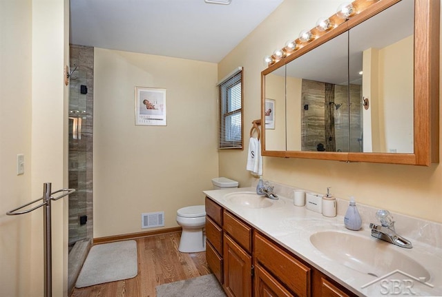 bathroom with vanity, walk in shower, toilet, and hardwood / wood-style floors