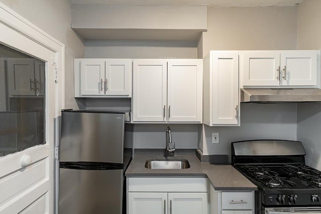 kitchen with gas stove, white cabinetry, sink, and stainless steel fridge