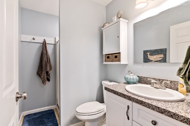 bathroom with toilet, a shower with door, and vanity