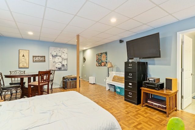 bedroom featuring a drop ceiling and light parquet floors