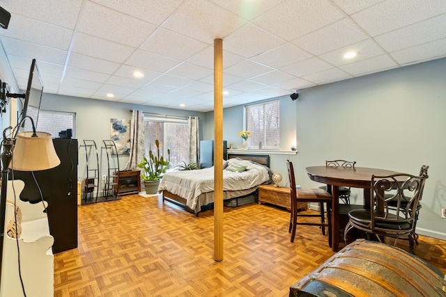 bedroom featuring a drop ceiling and light parquet floors