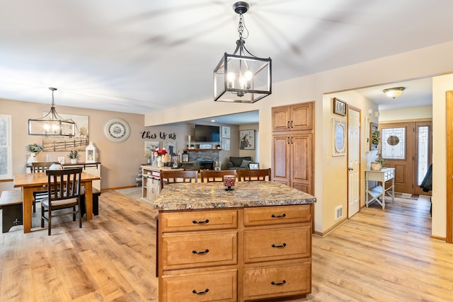 kitchen featuring hanging light fixtures, a notable chandelier, a center island, and a stone fireplace