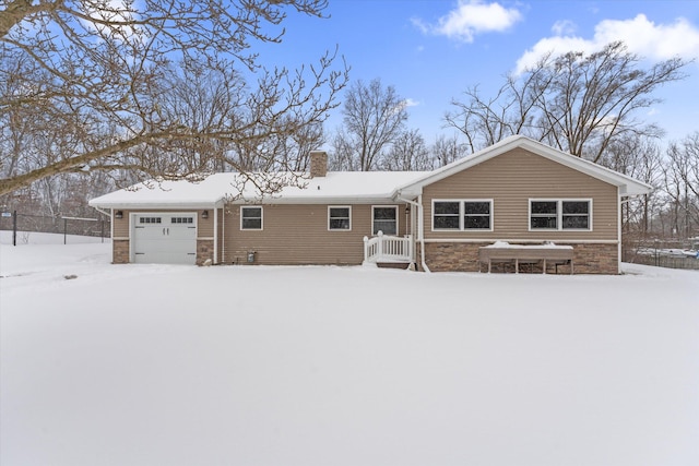 snow covered rear of property with a garage