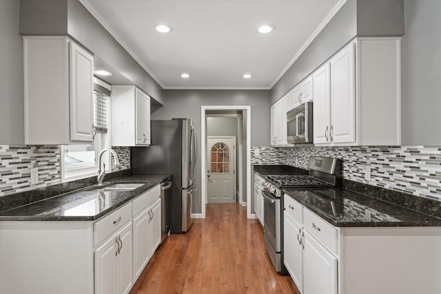 kitchen with stainless steel appliances, dark stone counters, hardwood / wood-style flooring, and white cabinetry