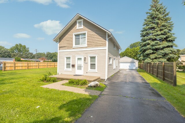 rear view of property with a garage, an outbuilding, and a lawn