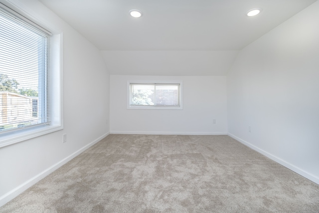 bonus room with lofted ceiling, a healthy amount of sunlight, and light carpet