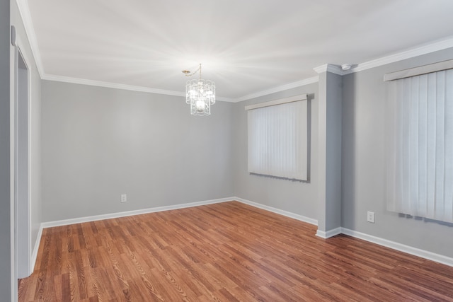 spare room with wood-type flooring, an inviting chandelier, and ornamental molding