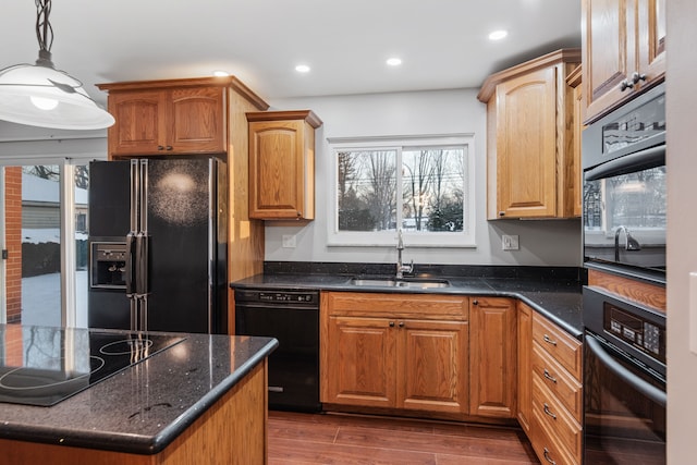 kitchen with dark wood-type flooring, decorative light fixtures, black appliances, dark stone countertops, and sink