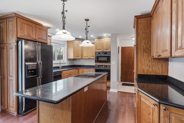 kitchen featuring dark stone countertops, black appliances, dark hardwood / wood-style flooring, a kitchen island, and decorative light fixtures