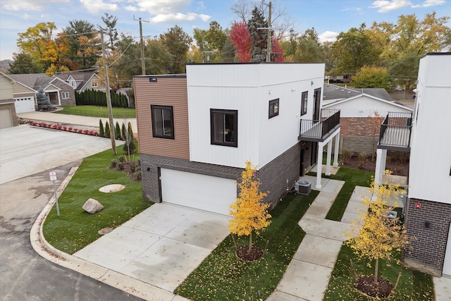 view of front of house with a garage, central AC, and a balcony