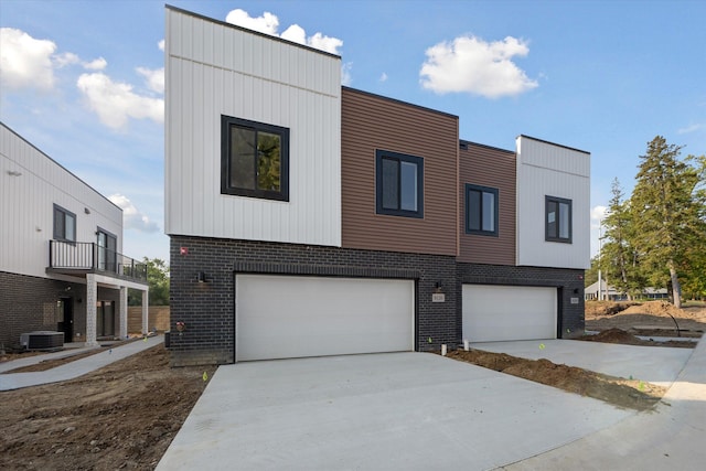 contemporary house featuring central AC unit and a garage