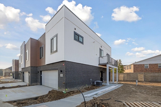 view of property exterior with a garage, central air condition unit, and a balcony