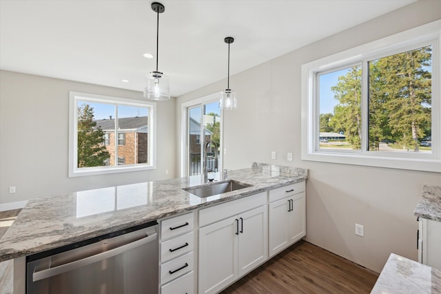 kitchen featuring pendant lighting, stainless steel dishwasher, sink, white cabinets, and light stone counters