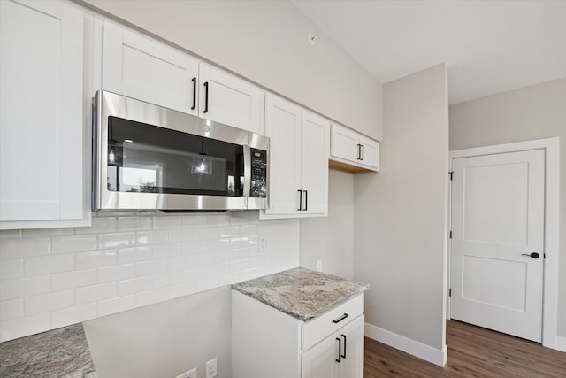 kitchen featuring tasteful backsplash, light stone countertops, dark hardwood / wood-style flooring, and white cabinetry