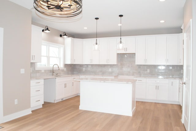 kitchen featuring sink, white cabinets, hanging light fixtures, and a center island