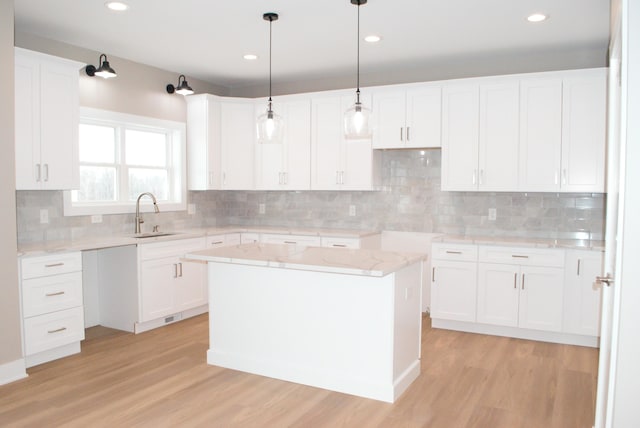 kitchen with backsplash, a center island, sink, light hardwood / wood-style flooring, and white cabinets