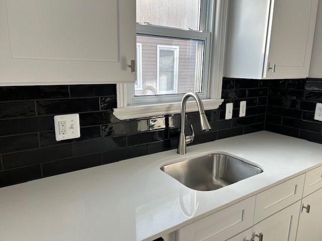 kitchen featuring sink, white cabinetry, and backsplash