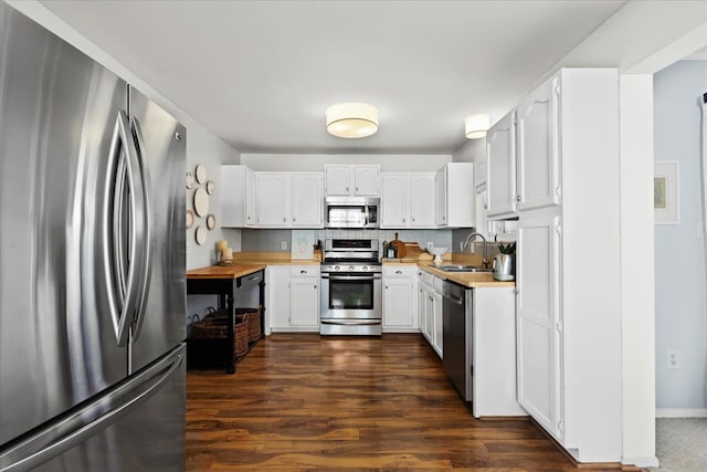 kitchen featuring white cabinets, wood counters, stainless steel appliances, decorative backsplash, and sink