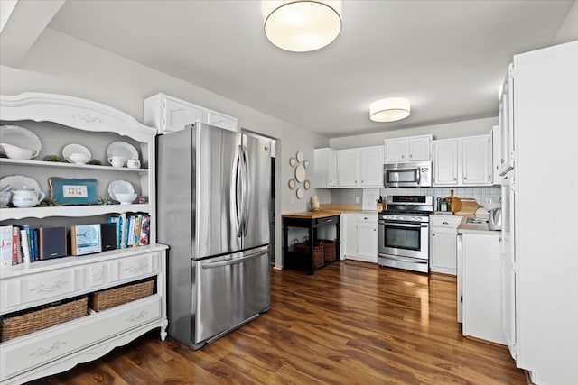 kitchen featuring white cabinets, tasteful backsplash, dark wood-type flooring, and appliances with stainless steel finishes