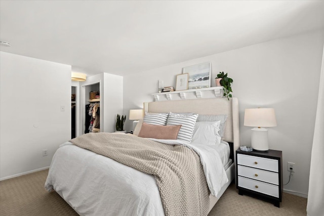 bedroom with a walk in closet, a closet, and light carpet