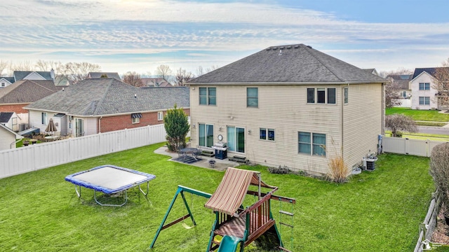 rear view of house with a patio, a playground, a lawn, and a trampoline