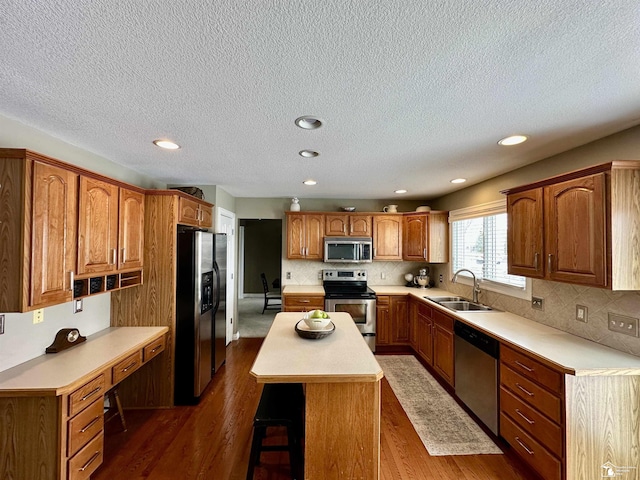 kitchen featuring stainless steel appliances, sink, a center island, dark hardwood / wood-style flooring, and a breakfast bar