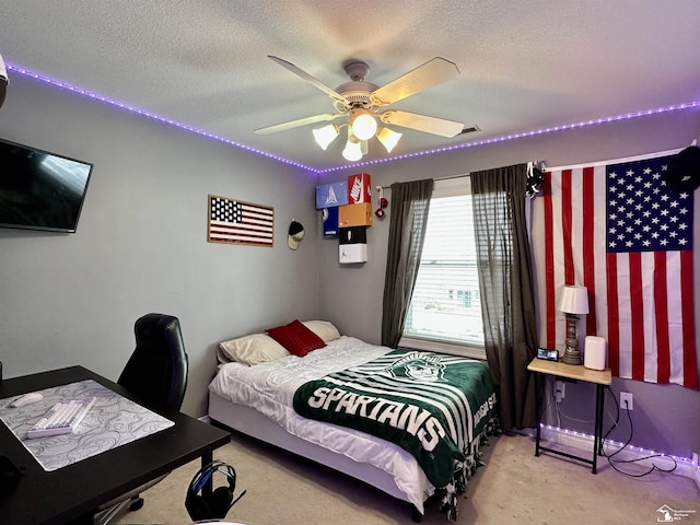 bedroom with ceiling fan, light carpet, and a textured ceiling