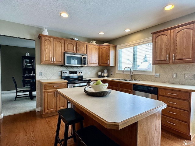 kitchen featuring hardwood / wood-style flooring, stainless steel appliances, a kitchen island, a breakfast bar area, and sink