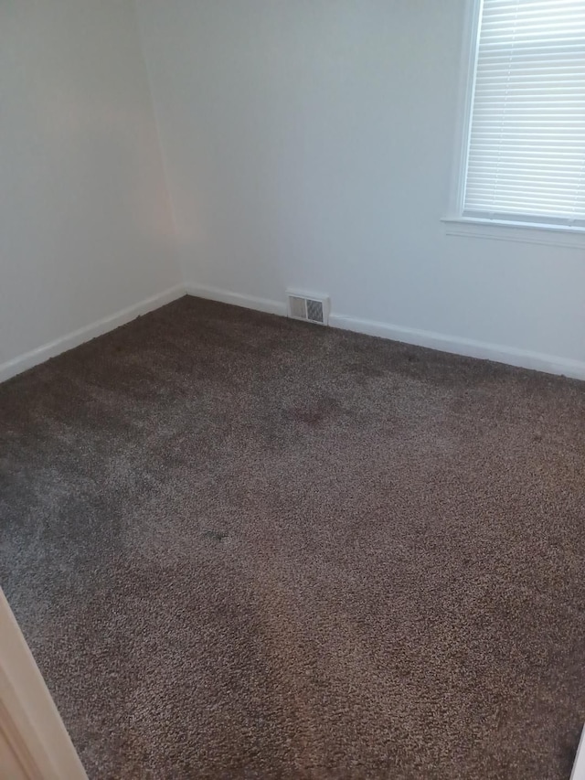 spare room featuring dark colored carpet