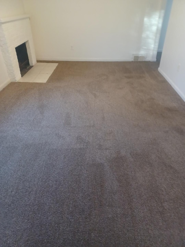 unfurnished living room with light carpet and a fireplace