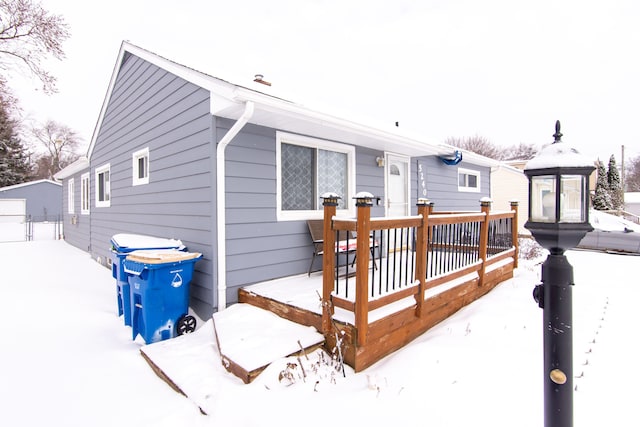 snow covered back of property with a wooden deck