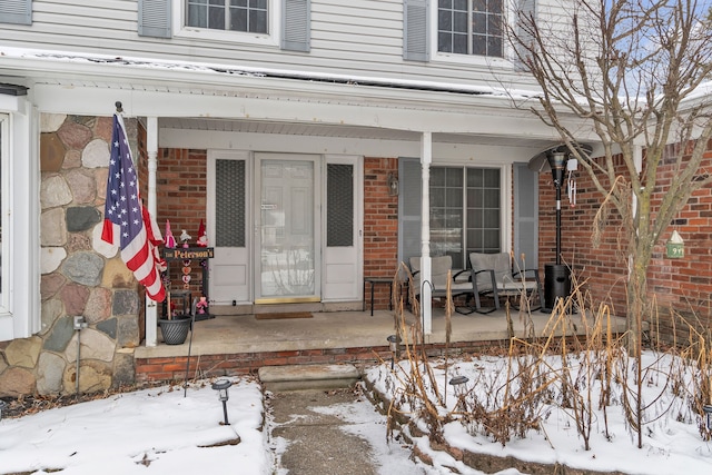 snow covered property entrance featuring covered porch