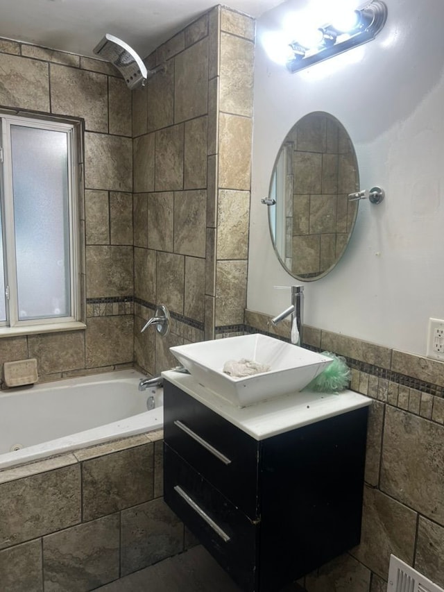 bathroom with tile walls, tiled shower / bath combo, and vanity