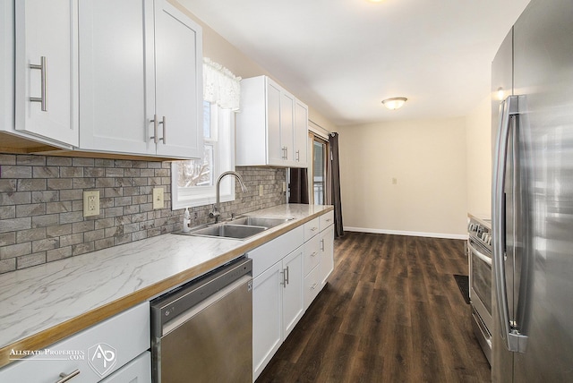 kitchen featuring appliances with stainless steel finishes, dark hardwood / wood-style floors, sink, white cabinetry, and tasteful backsplash