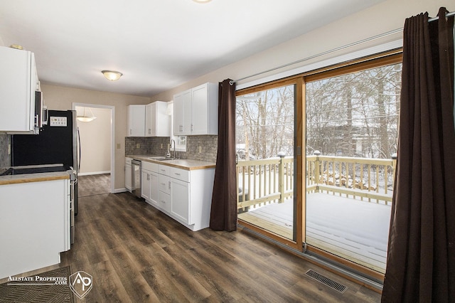 kitchen with stainless steel appliances, white cabinetry, sink, and dark wood-type flooring