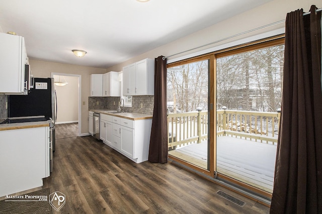 kitchen featuring stainless steel dishwasher, tasteful backsplash, a sink, white cabinetry, and light countertops